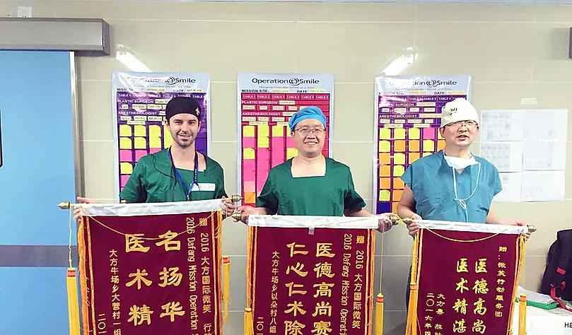 Three medical professionals with banners in a hospital.