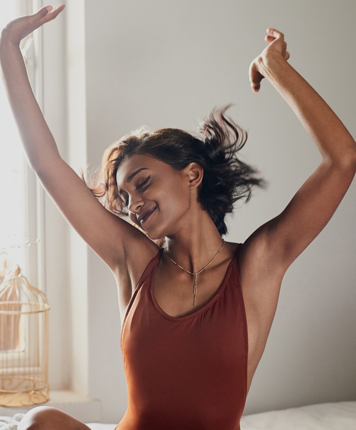 Woman joyfully dancing indoors in swimwear.