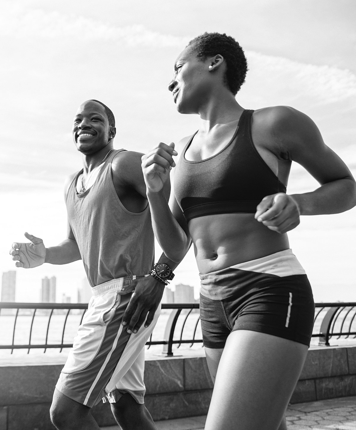 Couple jogging together along waterfront pathway.