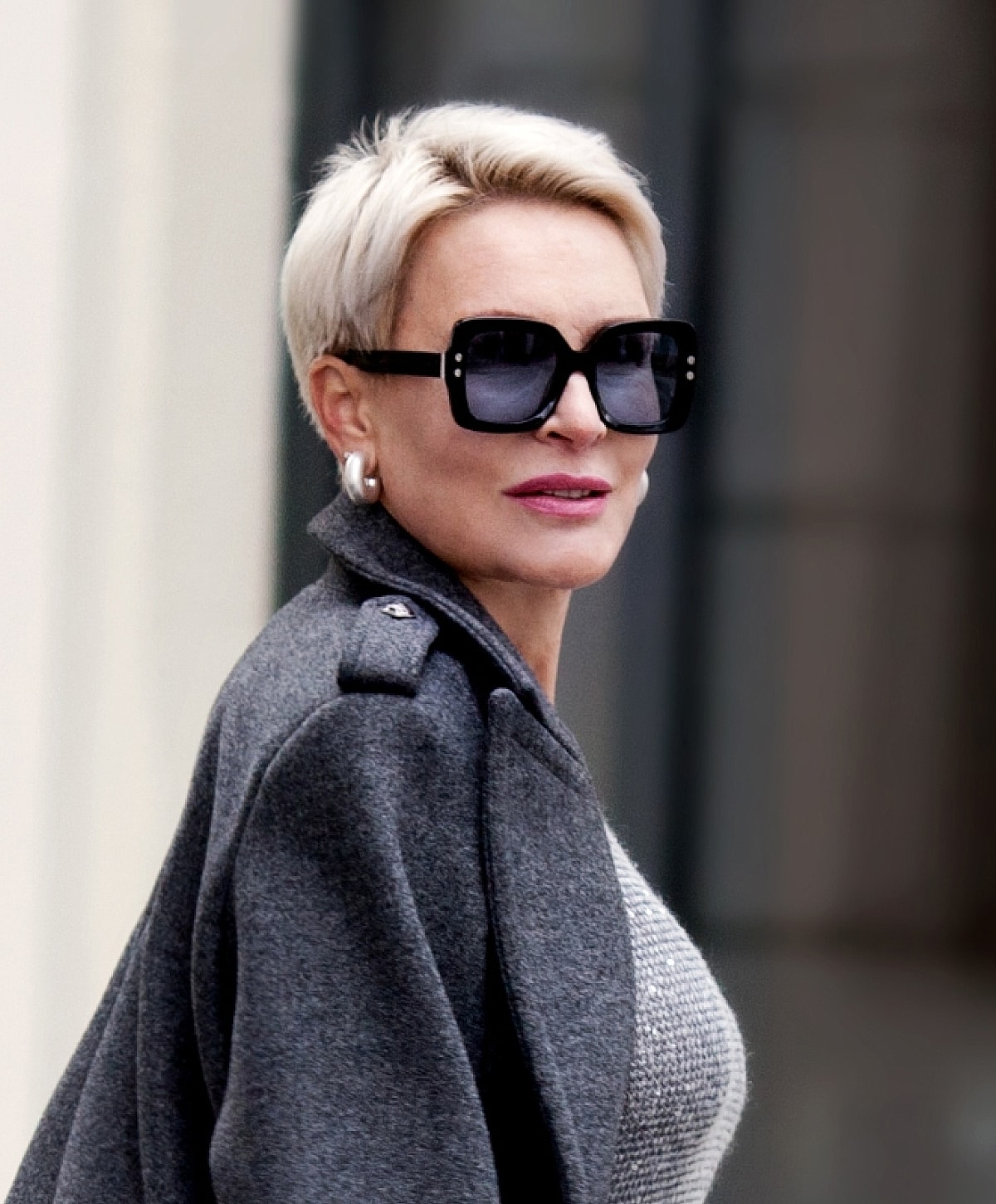 Stylish woman in sunglasses and gray coat.