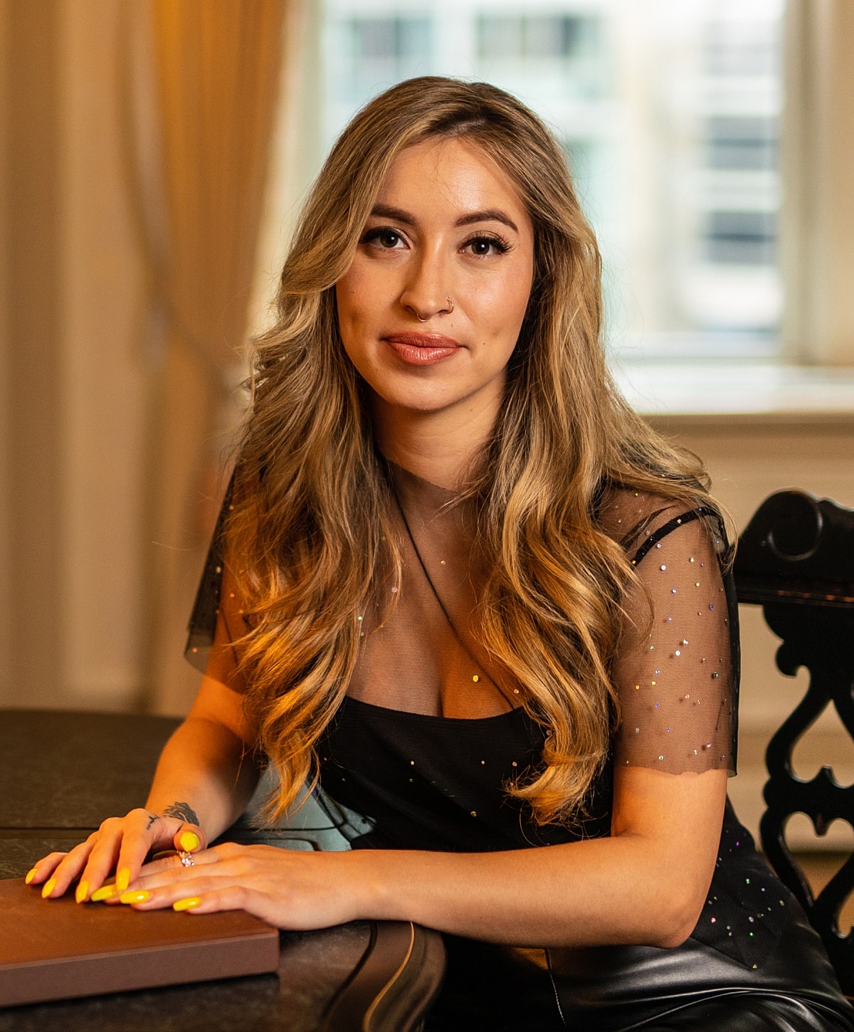 Woman with long hair sitting at a table.