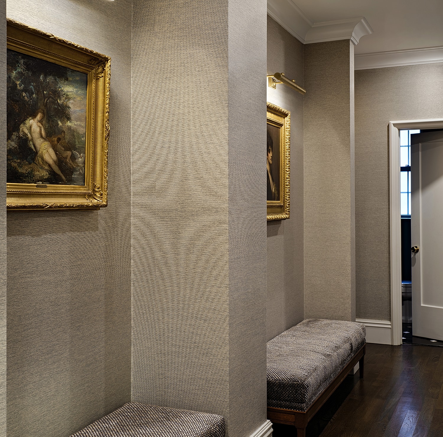 Elegant hallway with framed paintings and seating.
