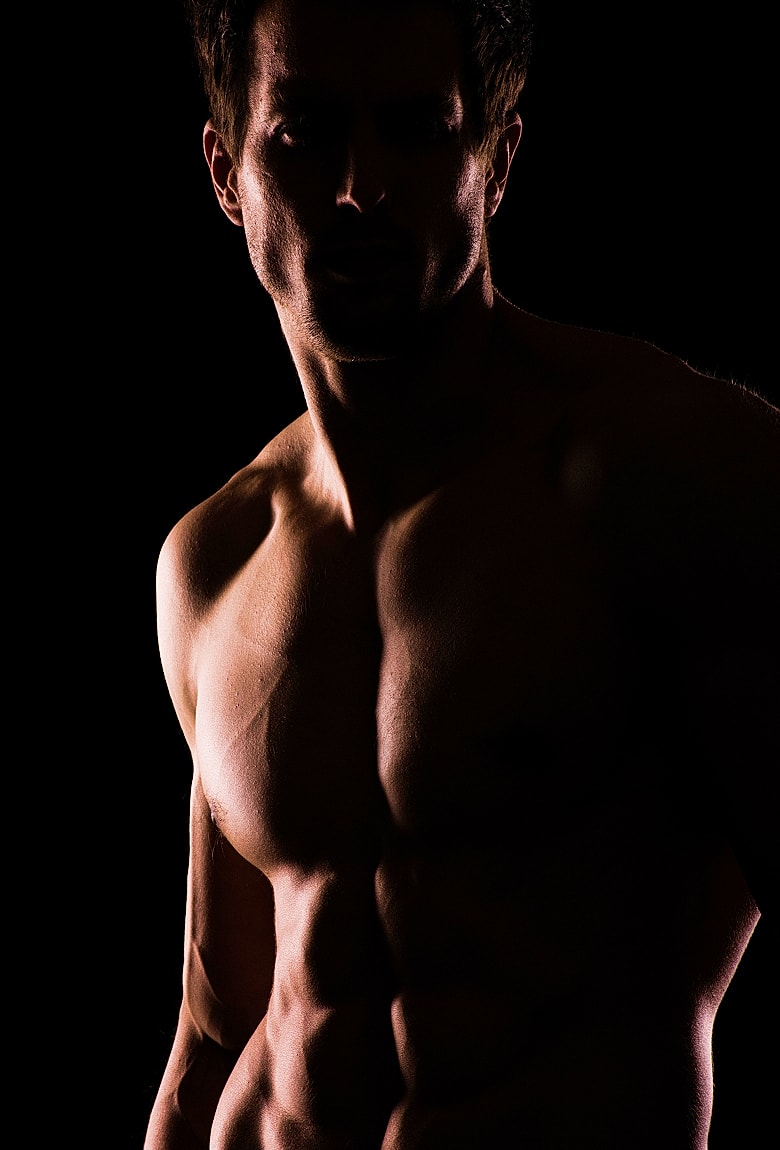 Shirtless man in dramatic lighting and shadows.