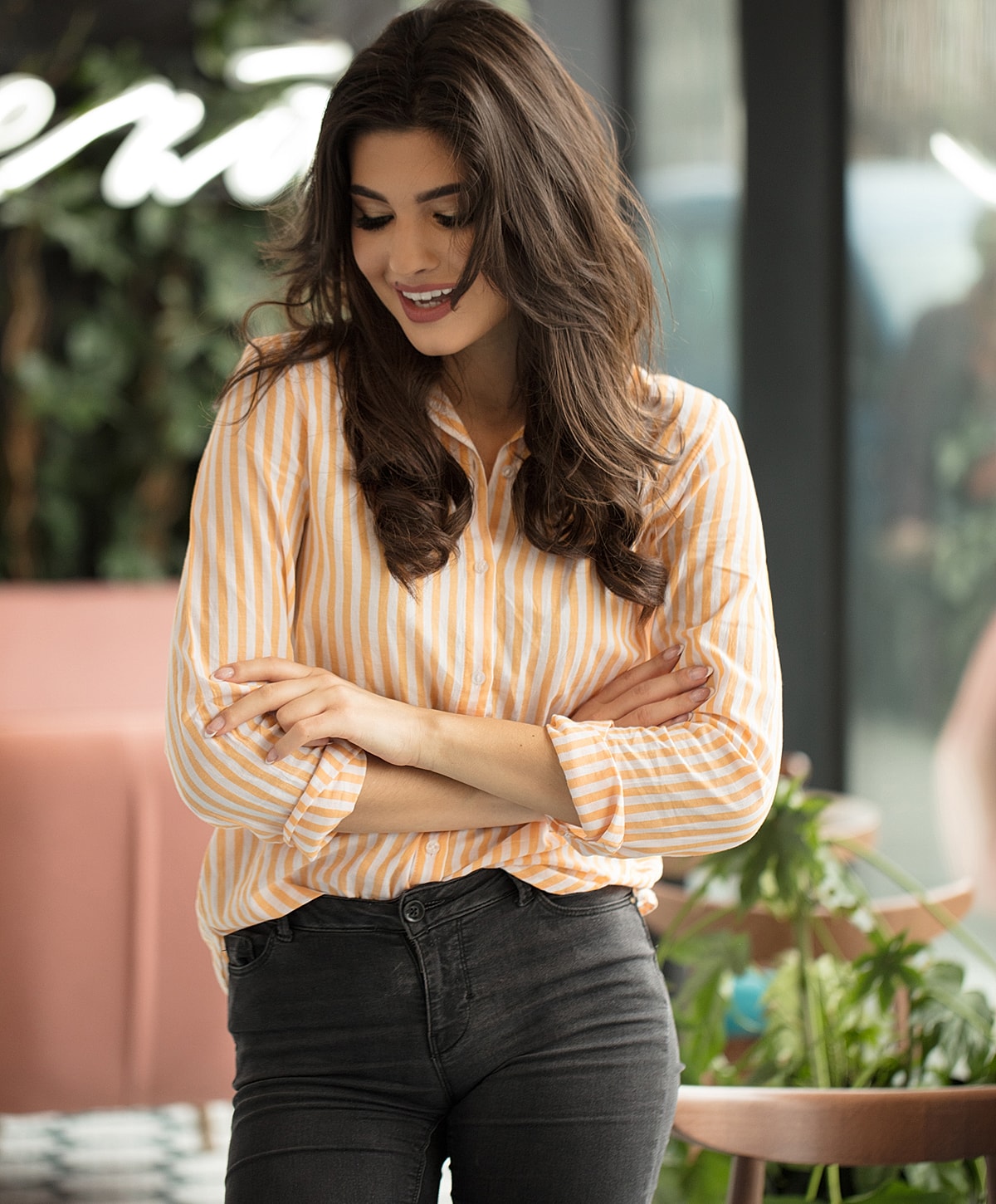Woman in striped shirt smiling indoors.