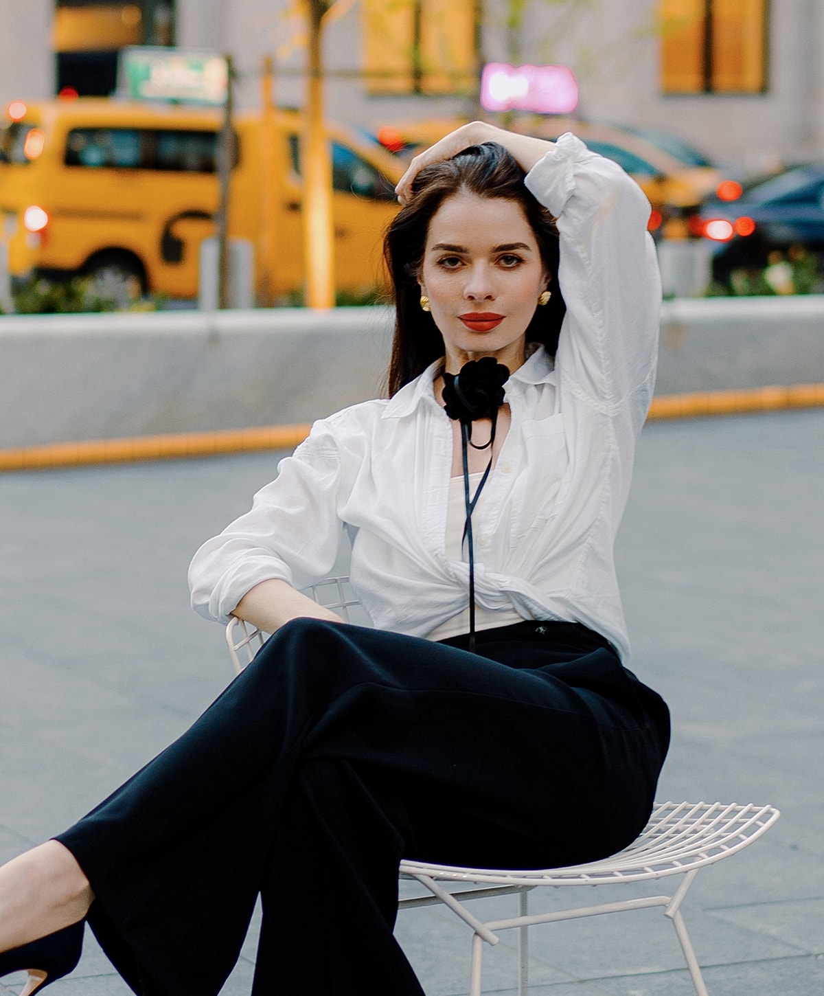 Woman in stylish outfit sitting outdoors.