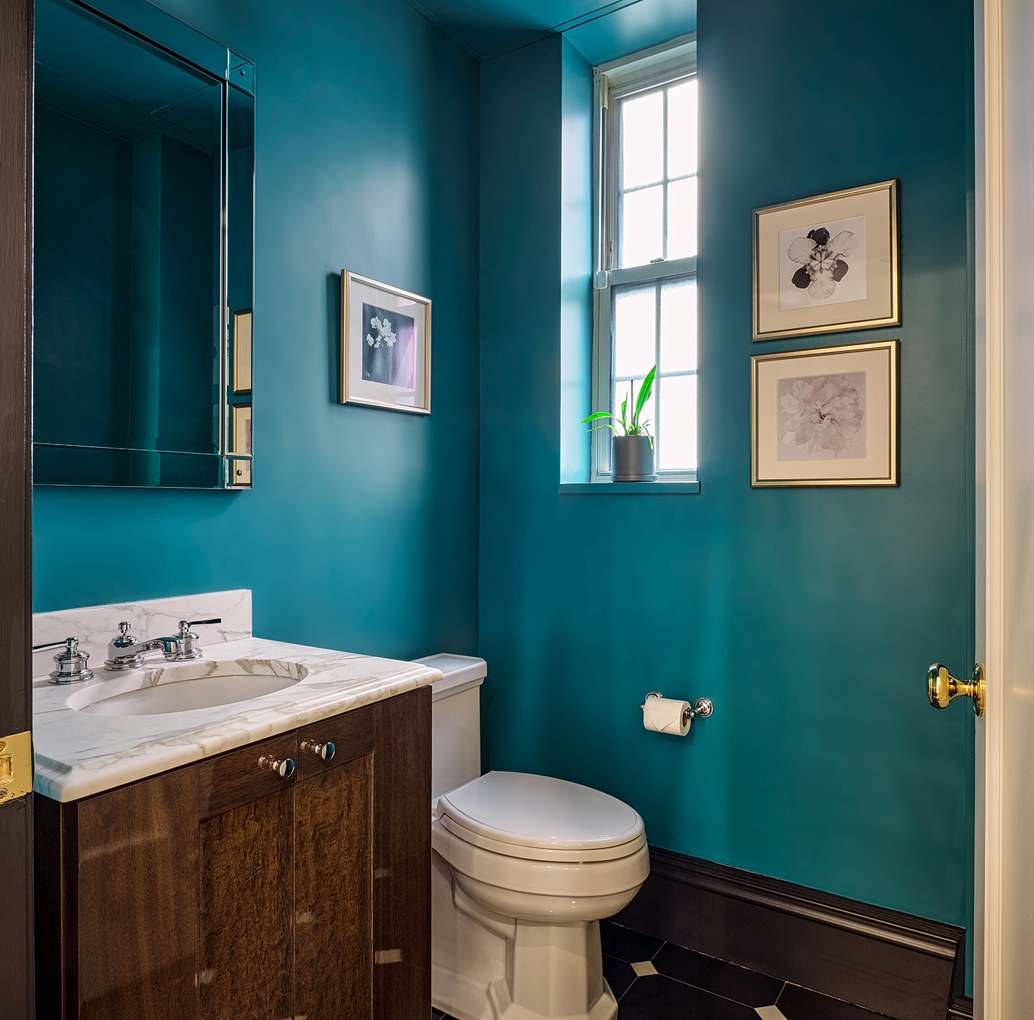 Modern bathroom with teal walls and natural light.