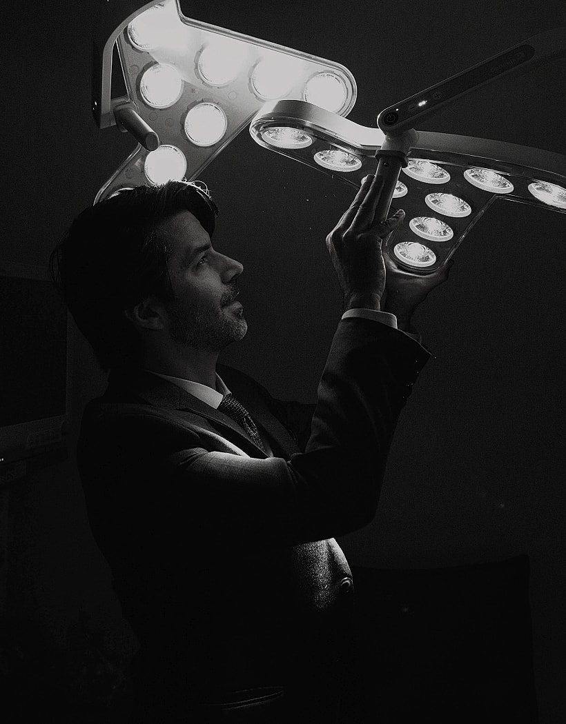 Man adjusting bright lights in dark setting.