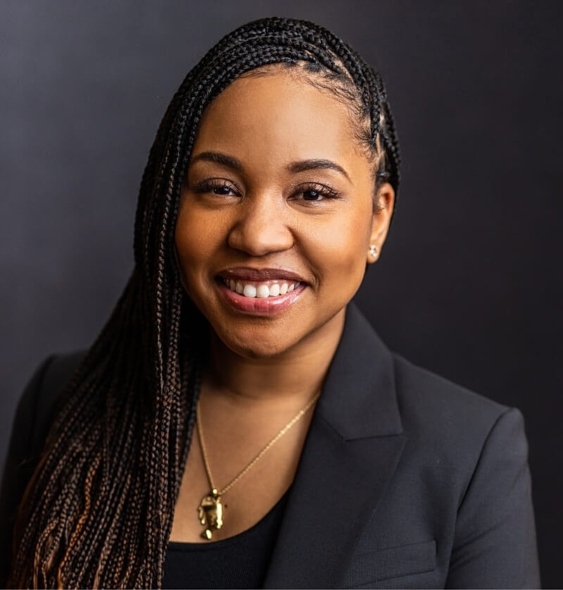 Smiling woman with braided hair and blazer.