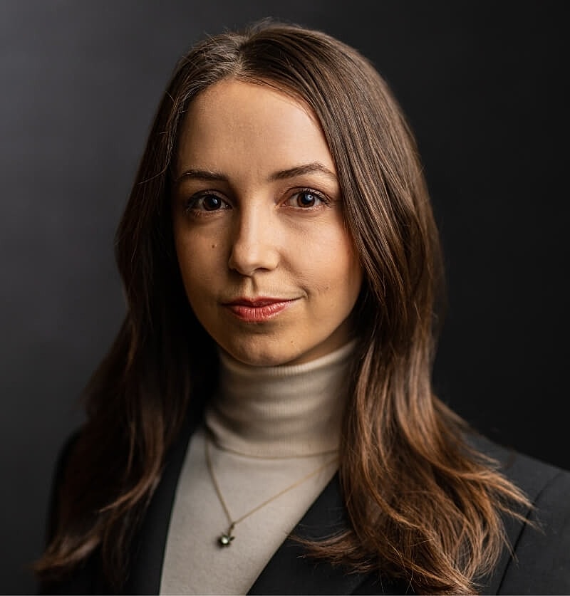 Professional woman with long hair and neutral background.