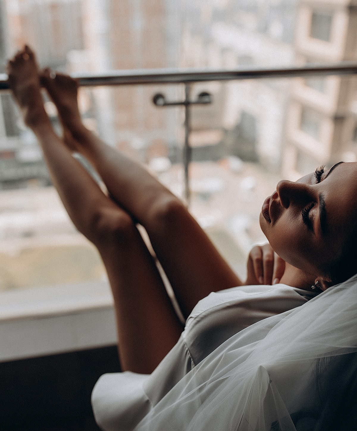 Woman relaxing by a window in soft lighting.