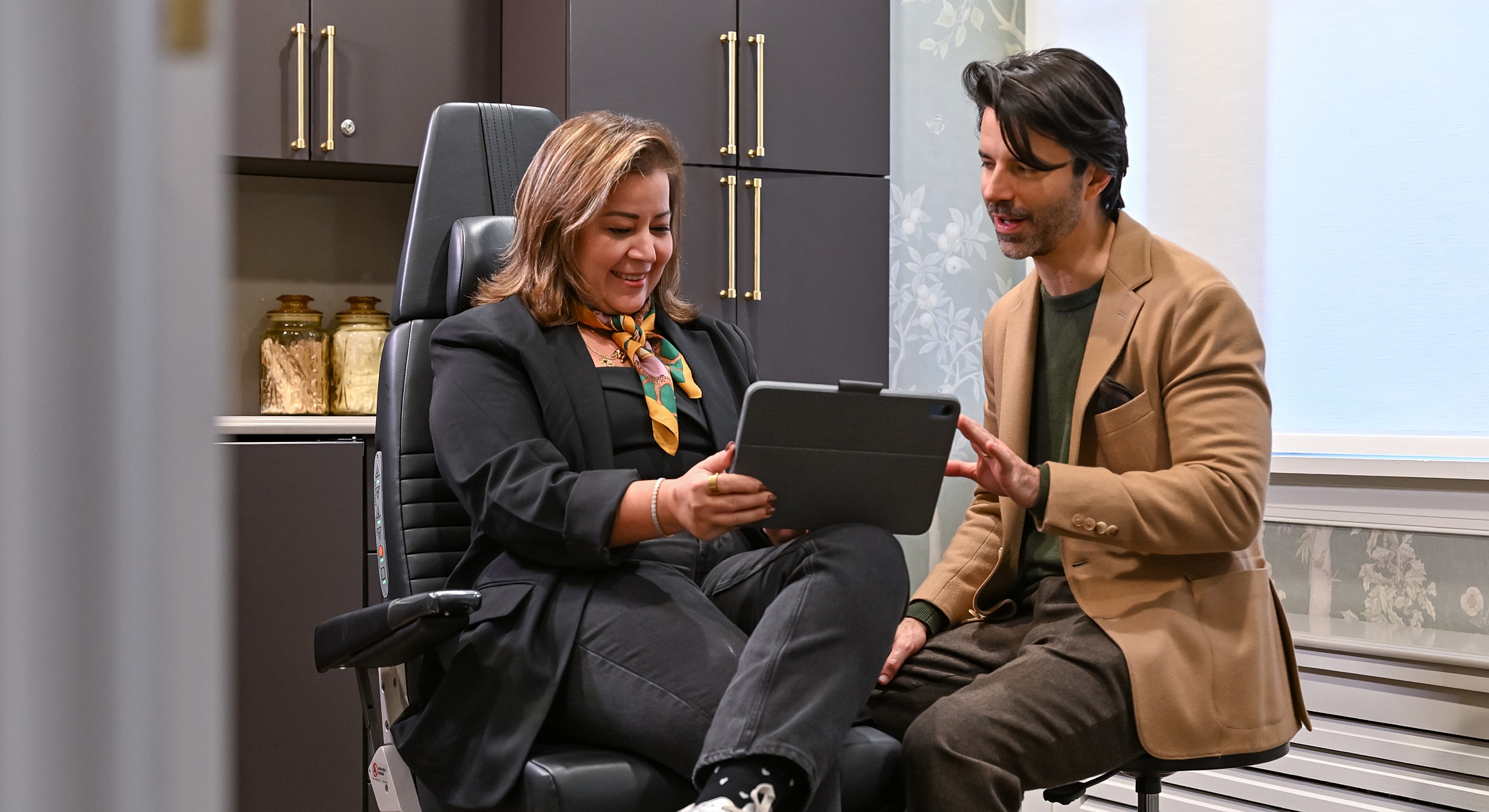 Two people discussing on a tablet in an office.