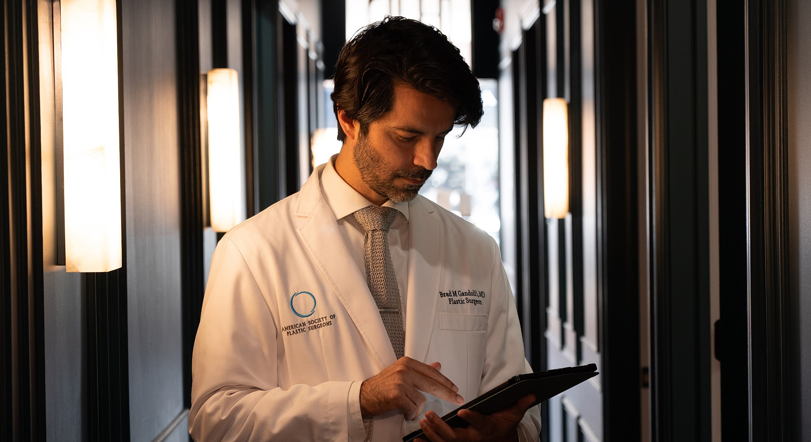 Doctor reviewing information in a dimly lit hallway.