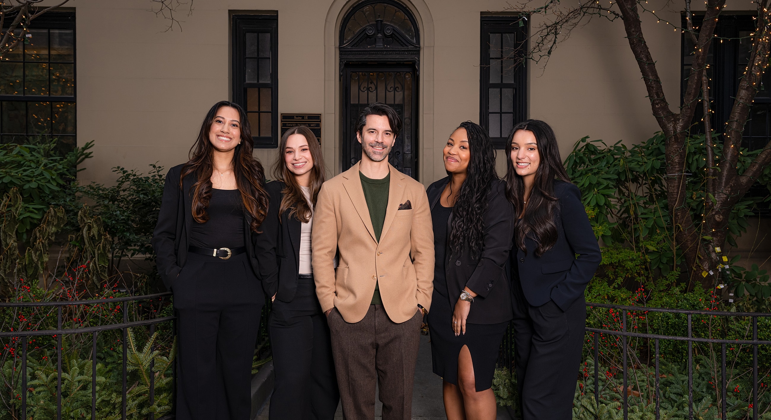Group photo of five professionals in formal attire.